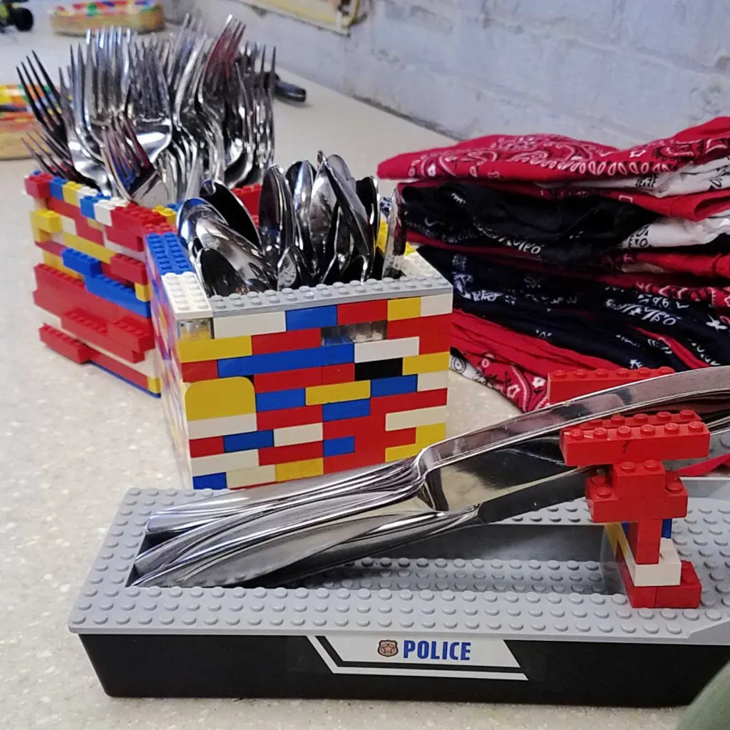 lego boat knife holder with boxes made from legos holding forks and spoons in background.