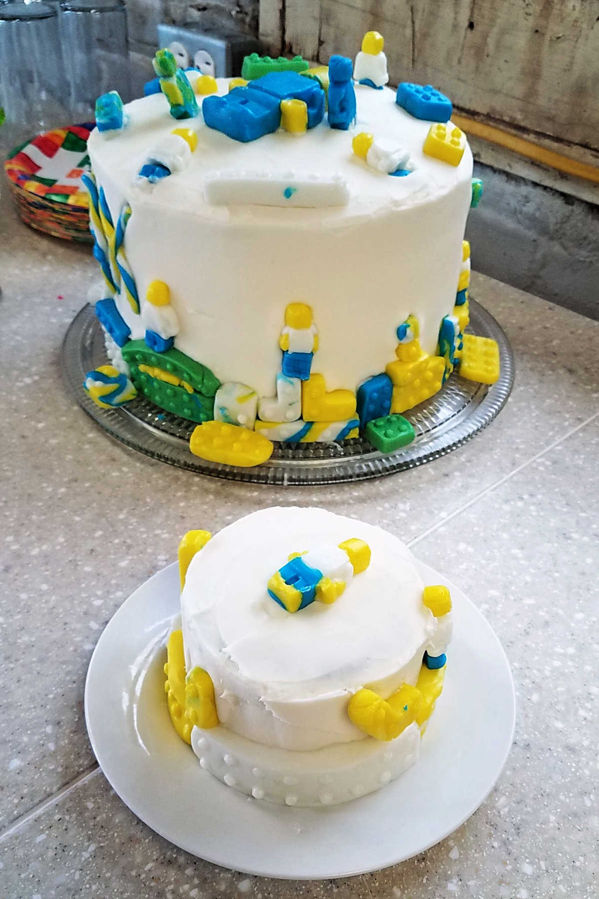 A small and large cake with marshmallow buttercream and decorated with fondant legos.