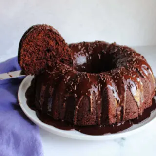 Lifting first slice of moist chocolate bundt cake out of cake.