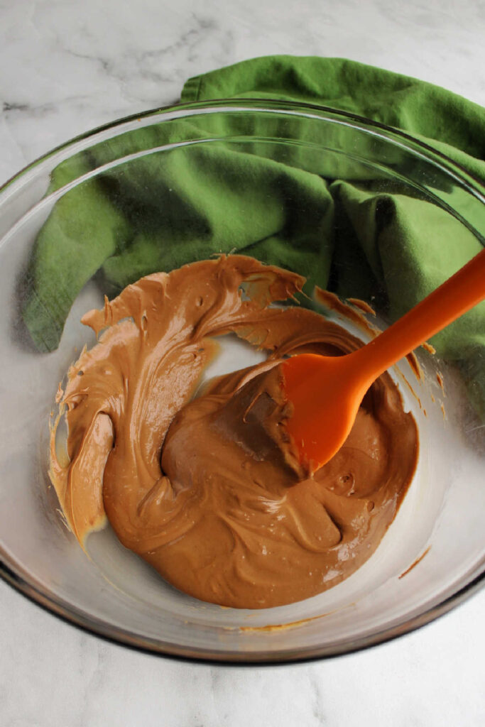 Peanut butter and chocolate melted together in glass bowl.