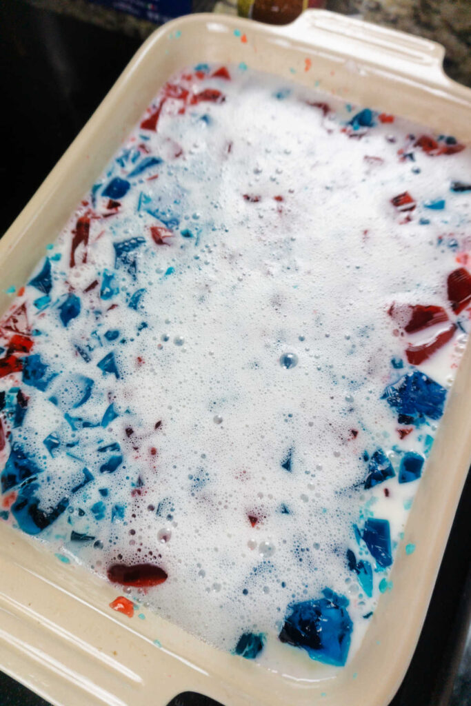 pan of white jello with cubes of red and blue jello in it, ready to set up in the fridge.