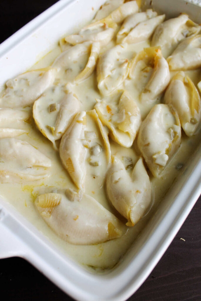 Pan of jumbo pasta shells stuffed with chicken and topped with white enchilada sauce.