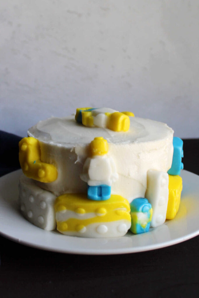 Small cake frosted with marshmallow buttercream and decorated with fondant blocks.
