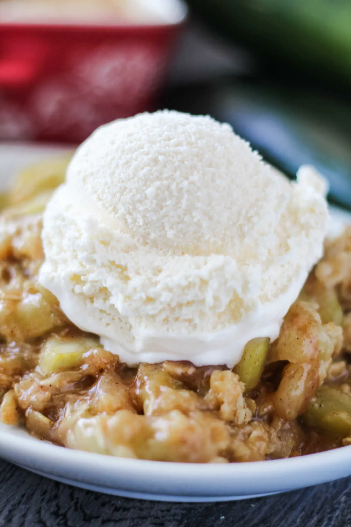 Serving of mock apple crisp made from zucchini topped with scoop of vanilla ice cream.
