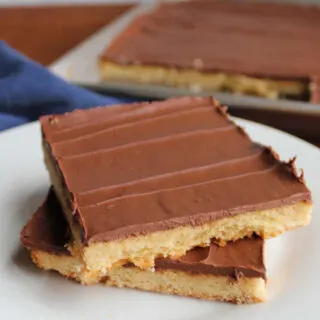Two toffee cookie bars topped with chocolate stacked on top of each other, ready to eat.