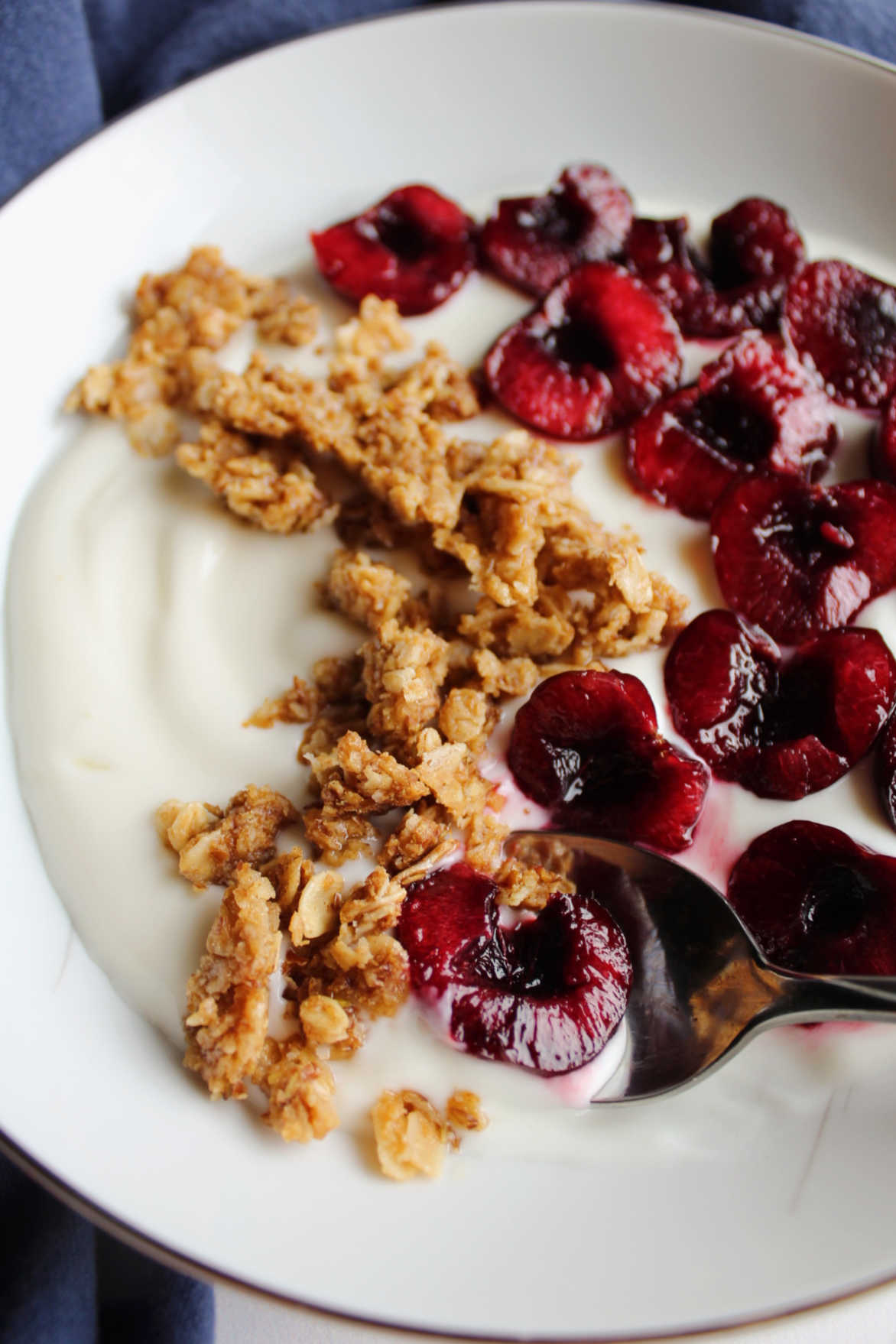 close up of bowl with yogurt, peanut butter granola and sweet cherries.
