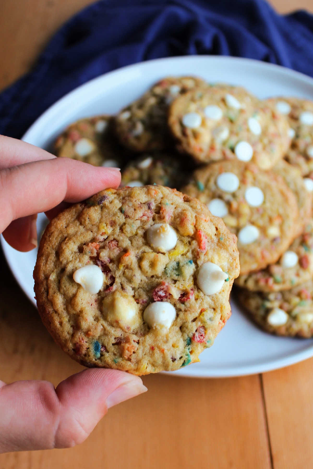 Hand holding fruity pebble cookie.