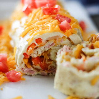 Looking at layers of spiraled denver omelet roll on plate showing ham, peppers and cheese inside.