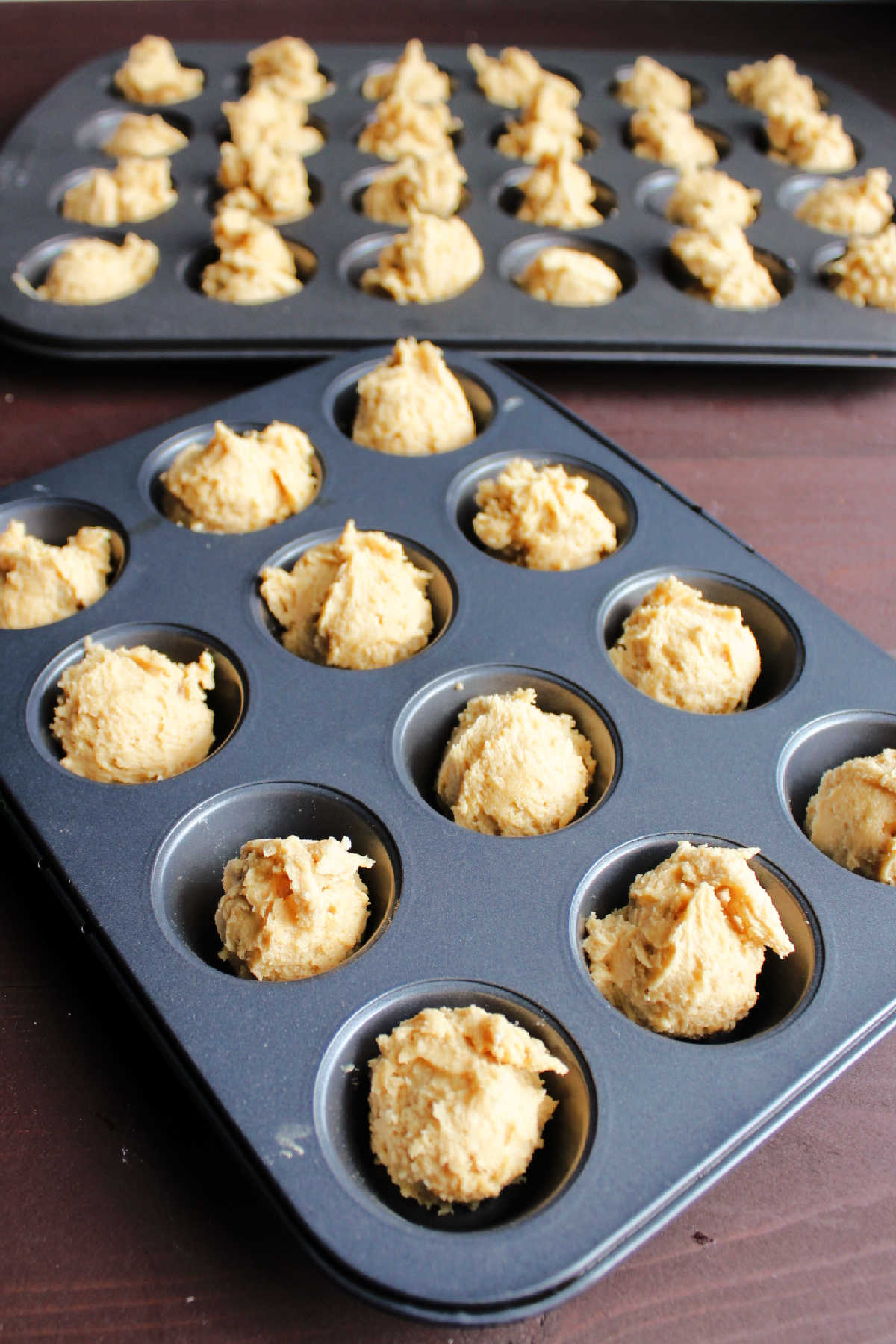peanut butter cookie dough in mini muffin tins ready to bake