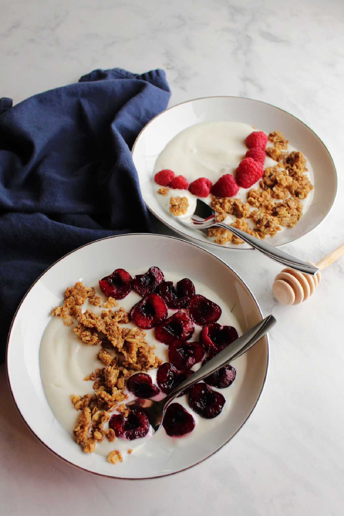 bowls of yogurt with cherries and raspberries and peanut butter granola