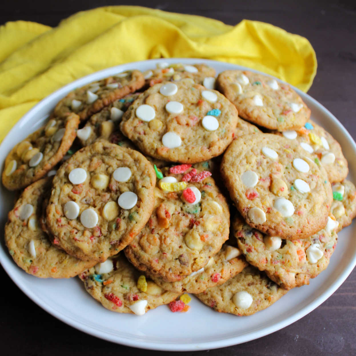 Plate piled high with fruity pebble cookies with white chocolate chips.