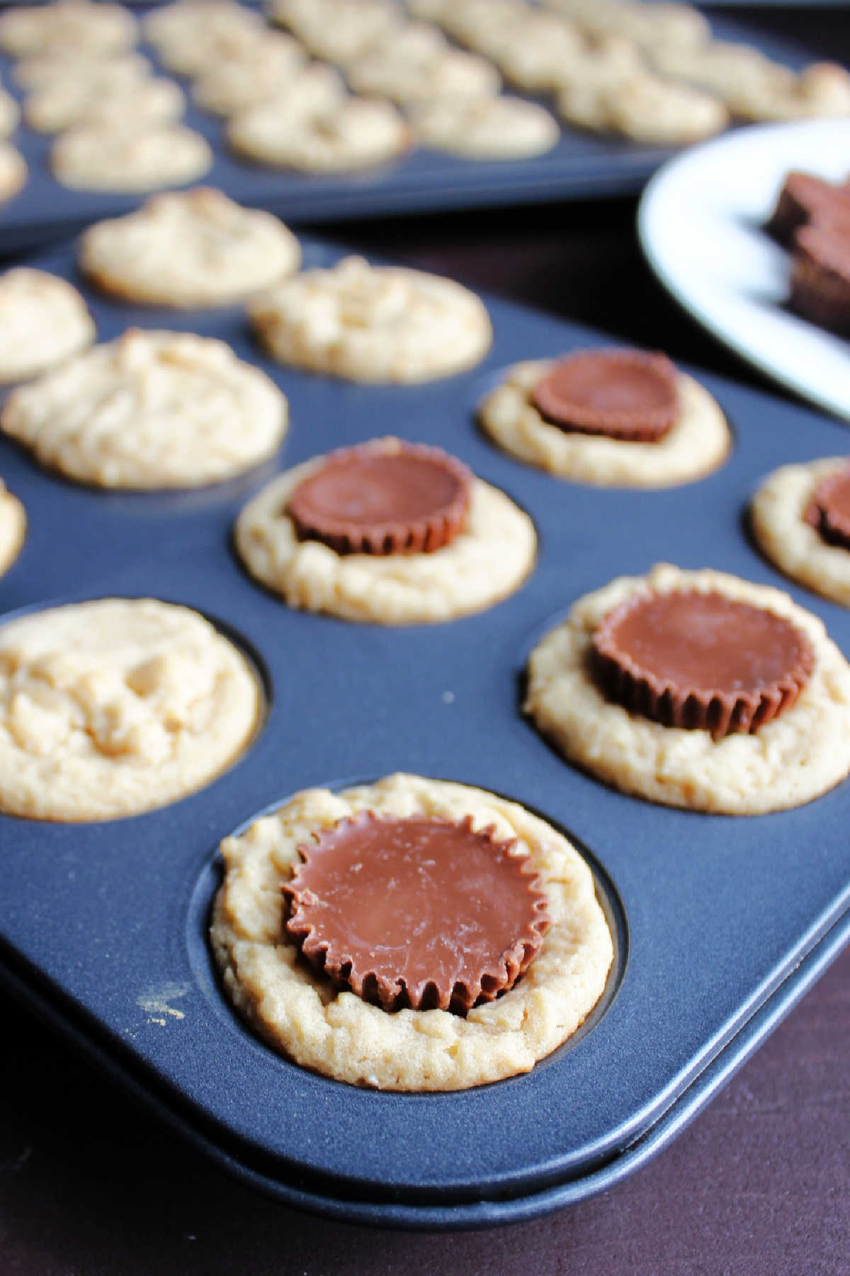 pushing mini peanut butter cup candies into hot freshly baked peanut butter cookies.