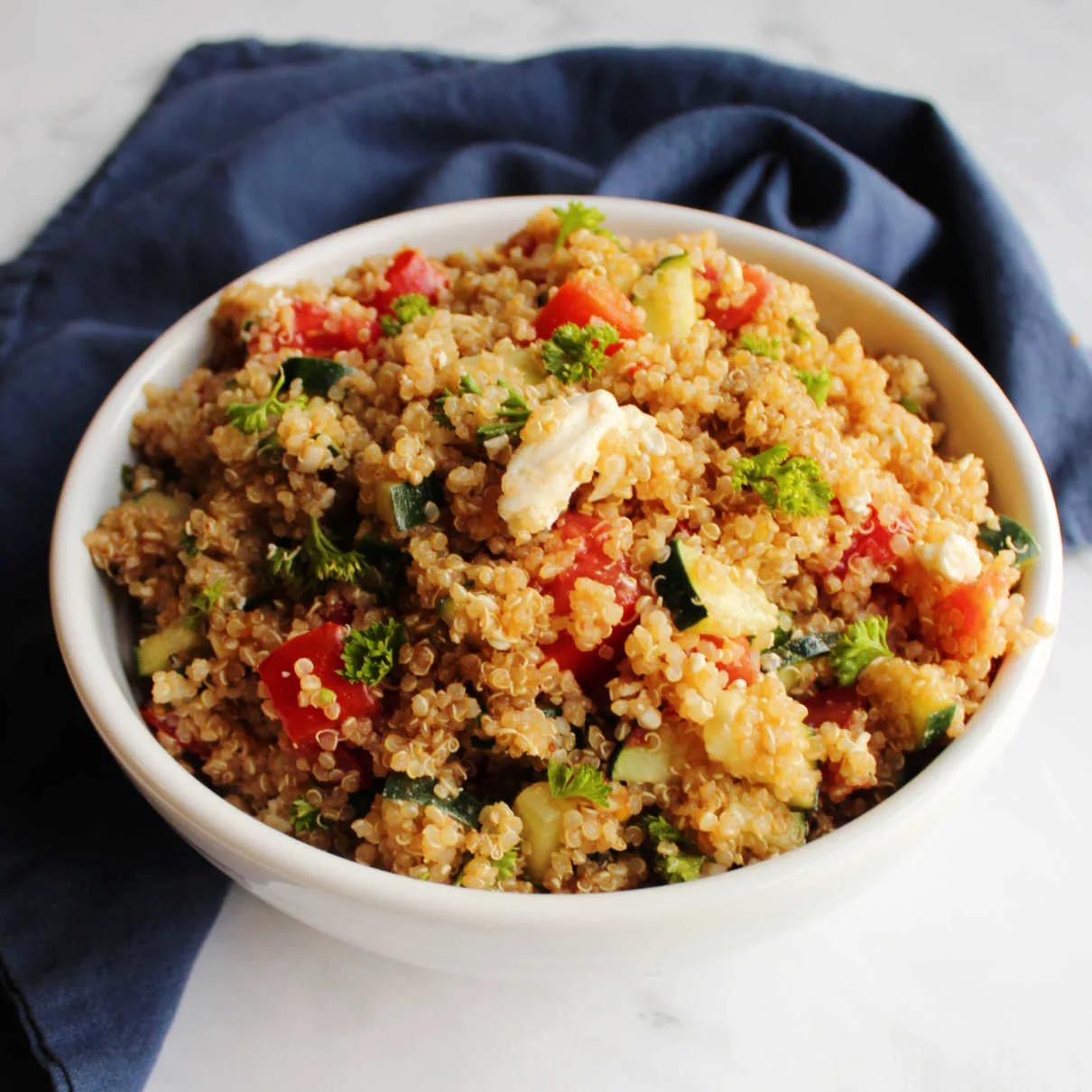 bowl of Mediterranean quinoa salad with tomatoes, cucumbers, feta and parsley.