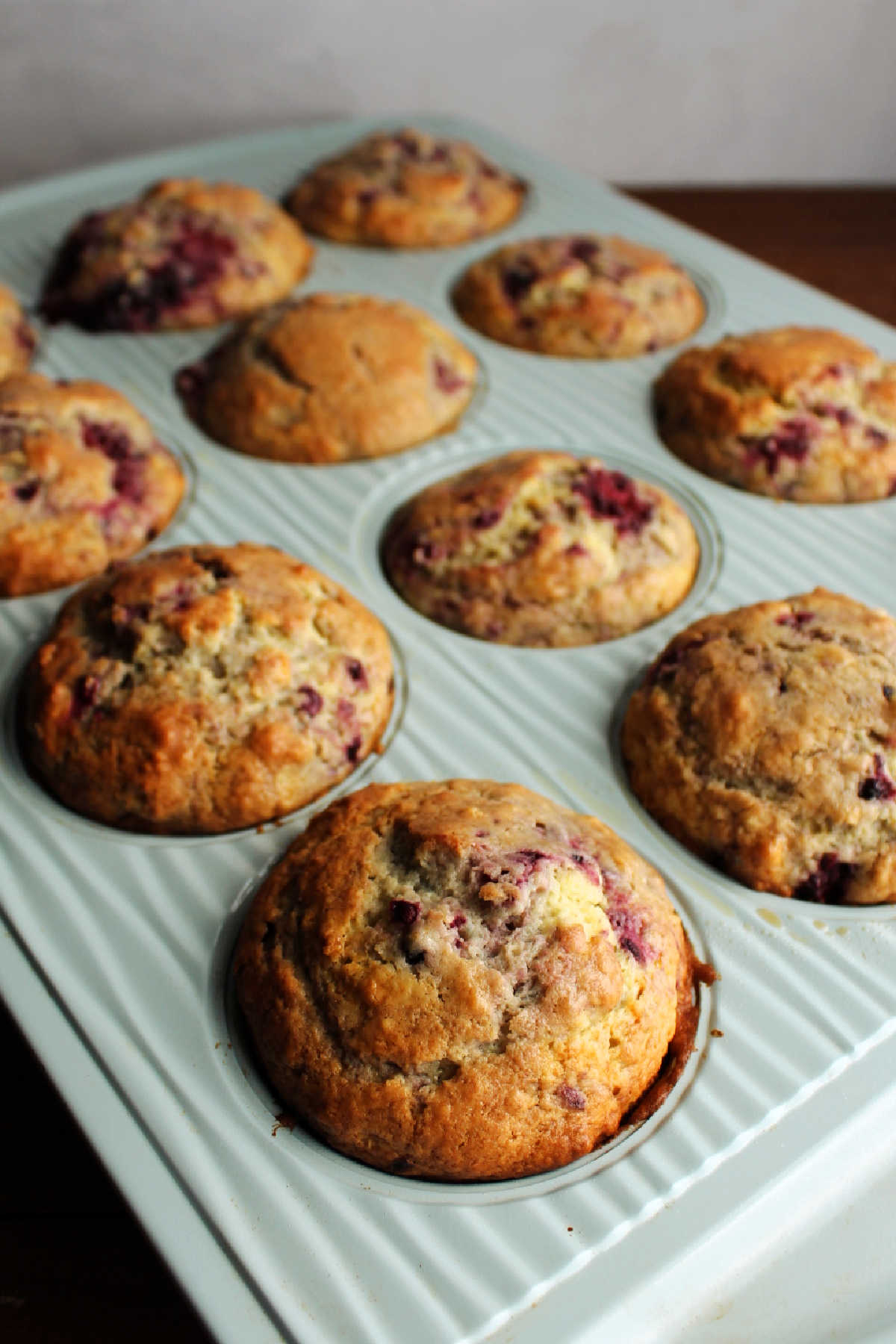 Muffin pan filled with freshly baked blackberry sour cream muffins.