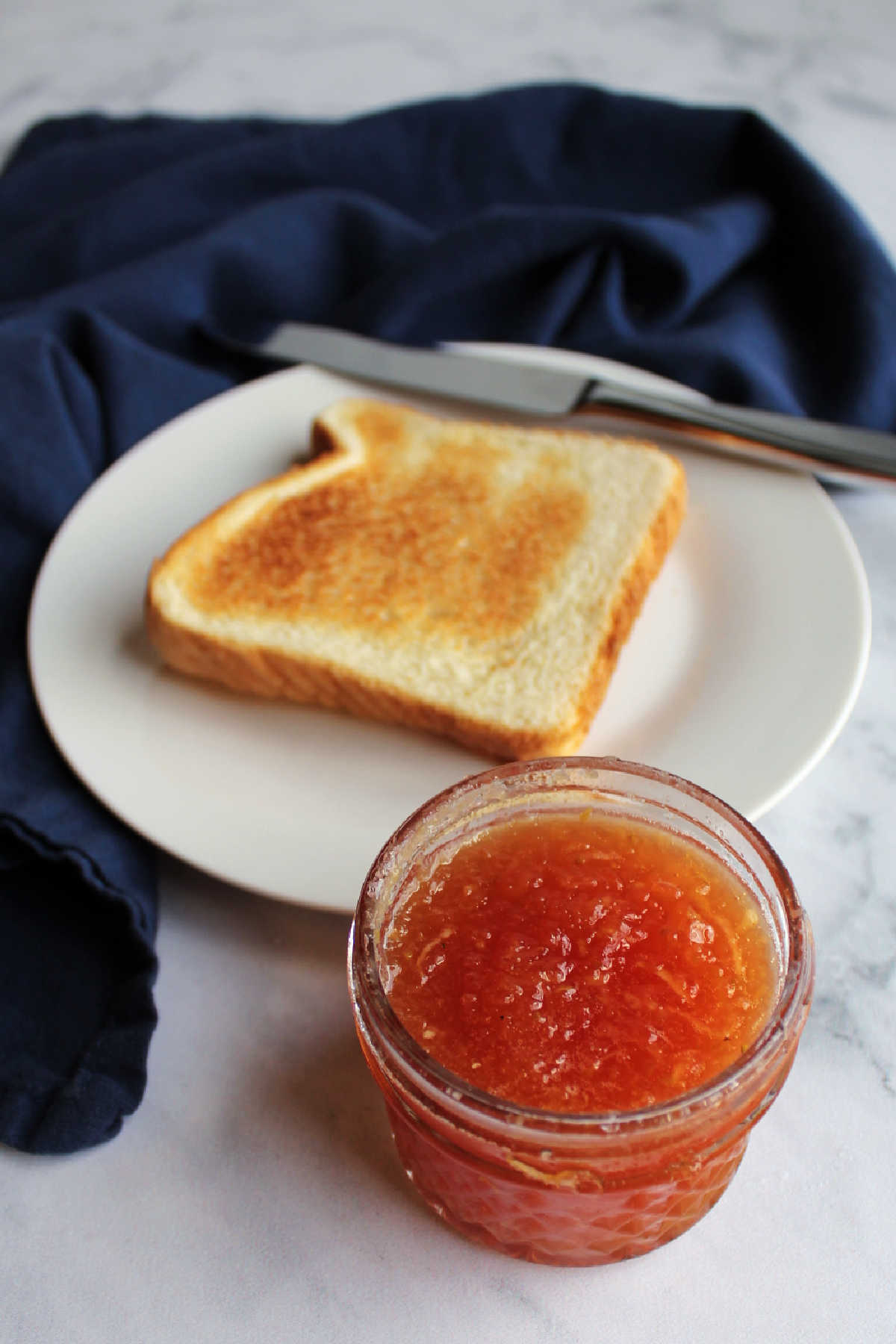 jar of strawberry zucchini jam in front of slice of toast.