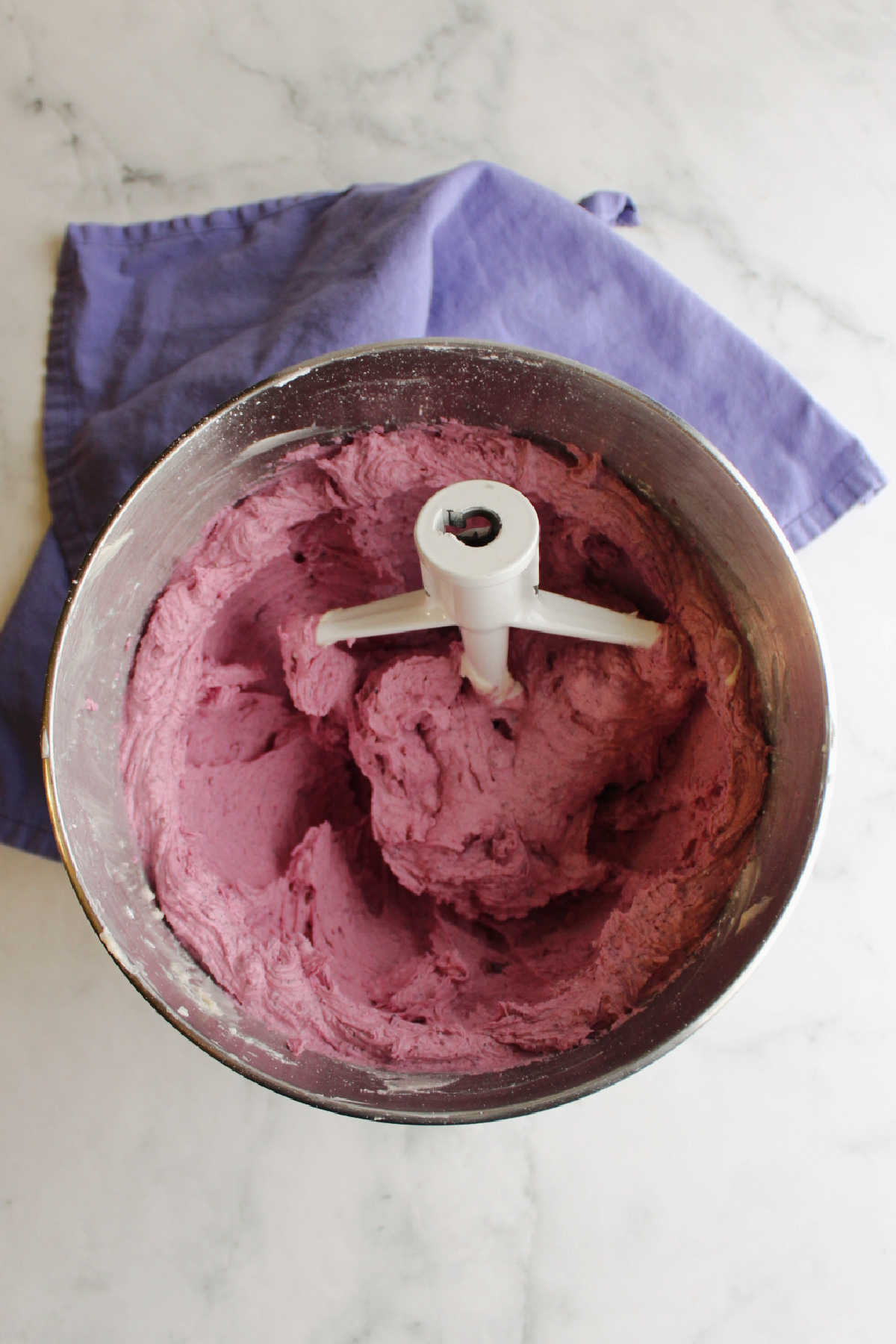 Mixer bowl filled with purple blueberry frosting.