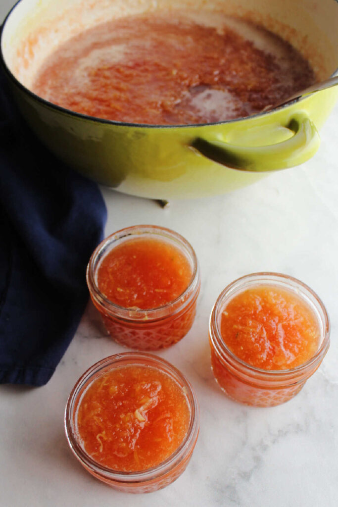 Hot zucchini jam spooned into small jars.