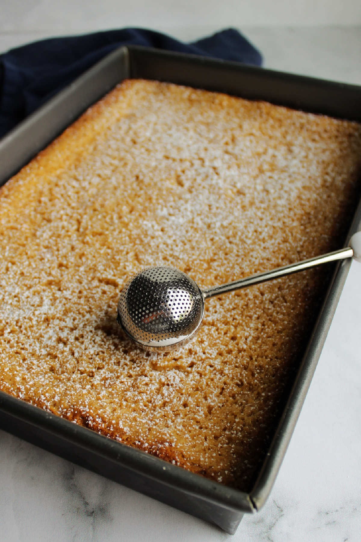Dusting powdered sugar over cooled apple gooey butter cake.
