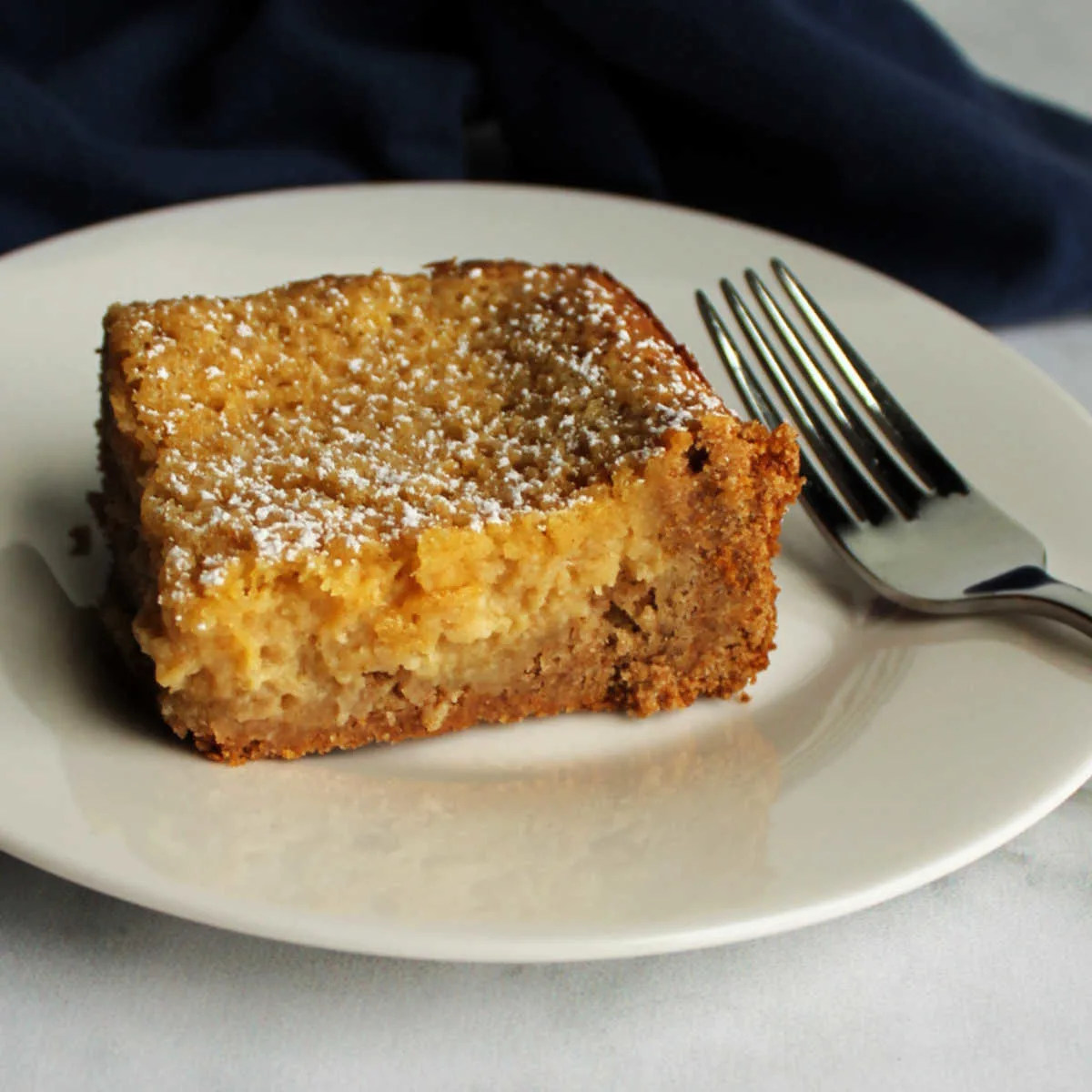 Piece of apple spice gooey butter cake with cakey crust and creamy filling.