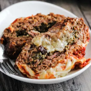 Slices of meatloaf topped with marinara and melted cheese and stuffed with more melted cheese on plate ready to eat.