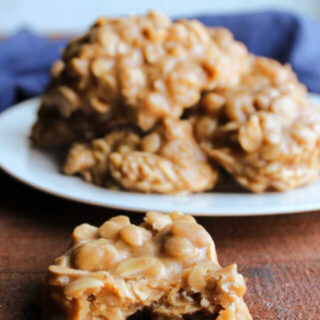 Peanut butter oatmeal no bake cookie with bite missing showing dense texture in front of plate of more cookies.