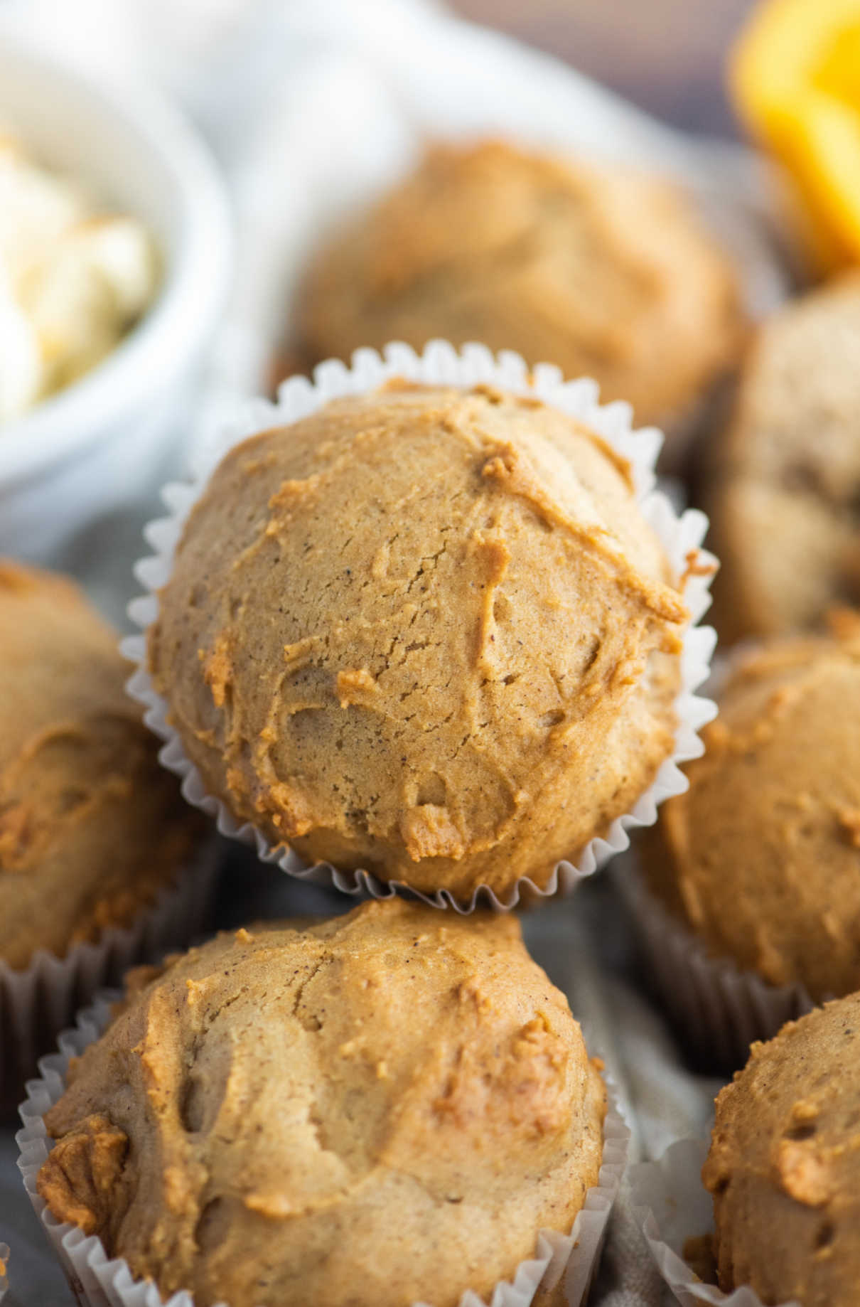 Freshly baked orange spice muffins with white paper wrappers.