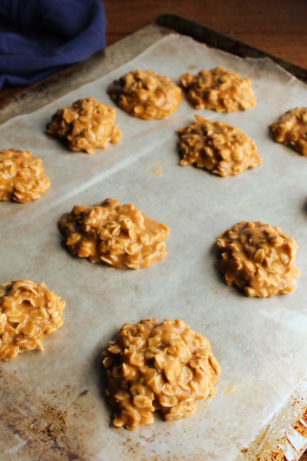Peanut butter no bake cookies setting up on a wax paper lined cookie sheet.