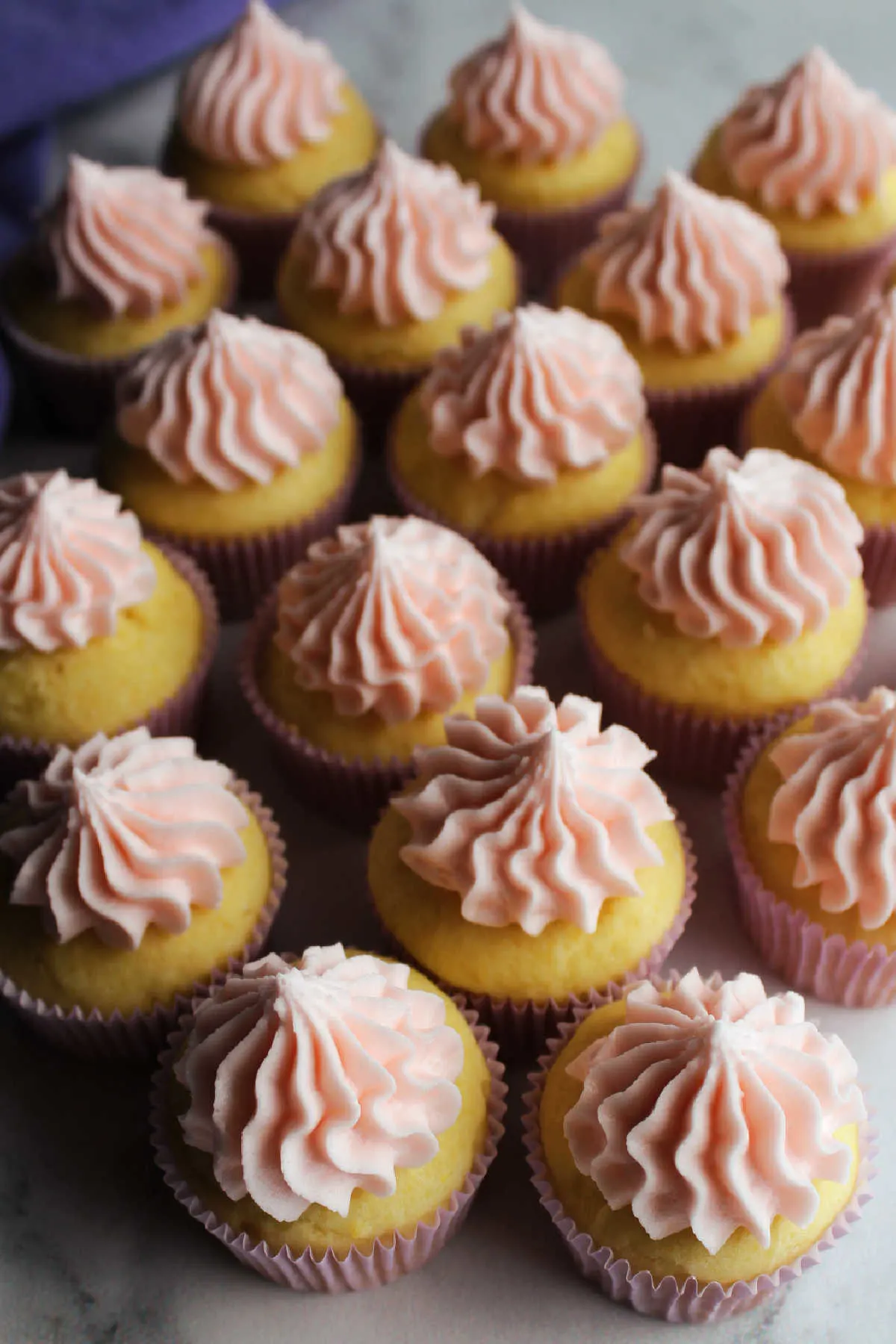 Looking down on cupcakes topped with pink lemon buttercream. 