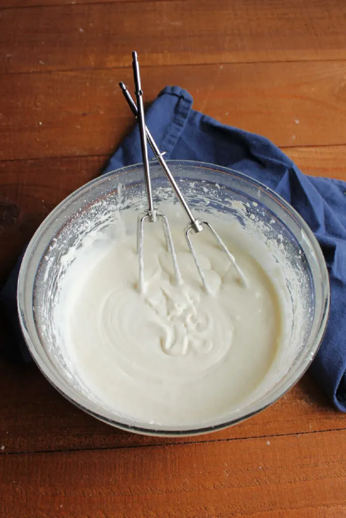 Bowl of sour cream frosting with mixer beaters, ready to spread over cake.