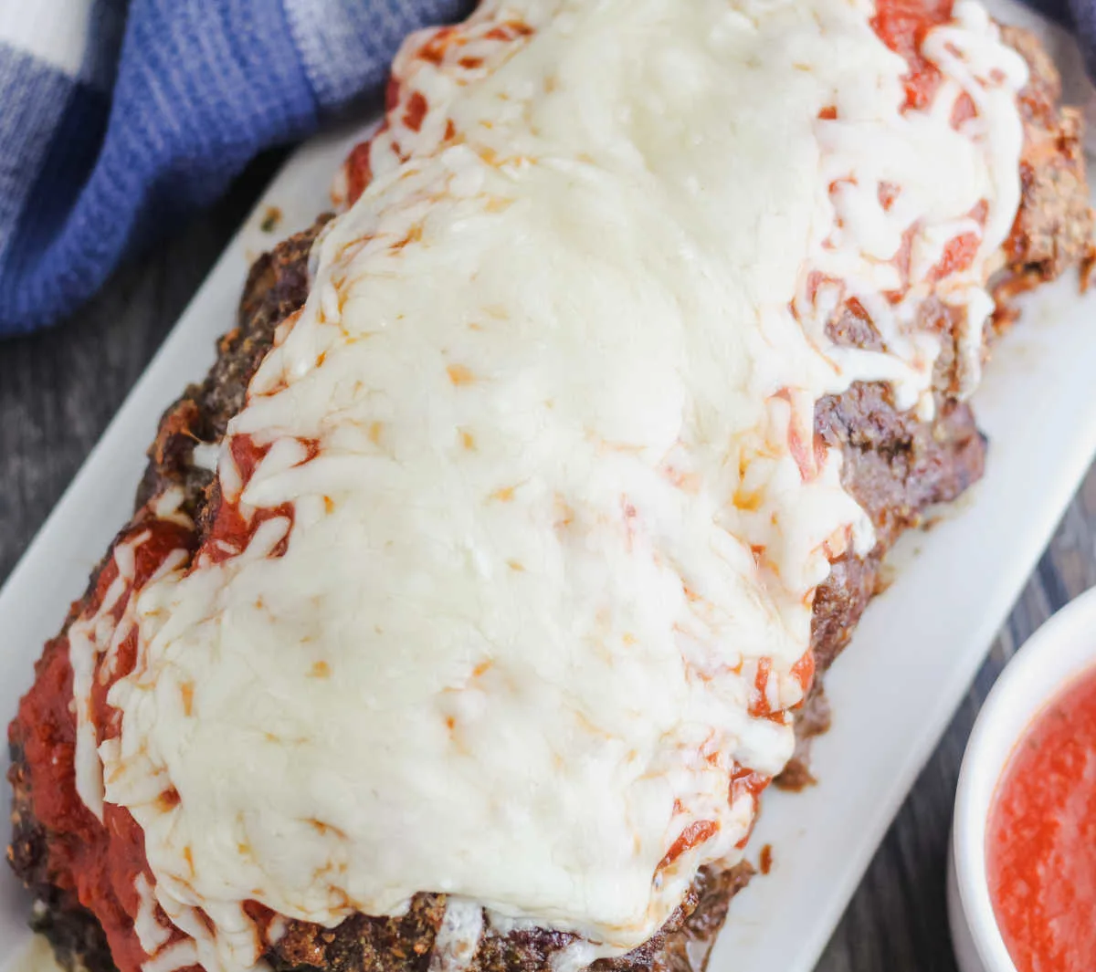 whole meatloaf topped with marinara sauce and melted cheese.