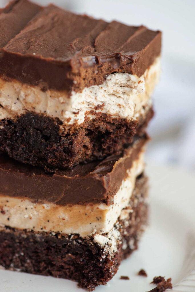 Close stack of coffee and cream brownies with layers of brownie, coffee frosting and ganache with bite missing from a corner.