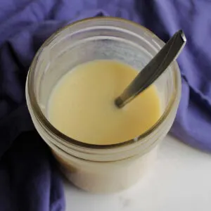 Looking down into jar of sweetened condensed milk with spoon.