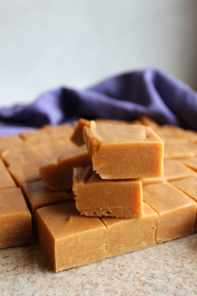Smooth creamy squares of peanut butter fudge on cutting board.