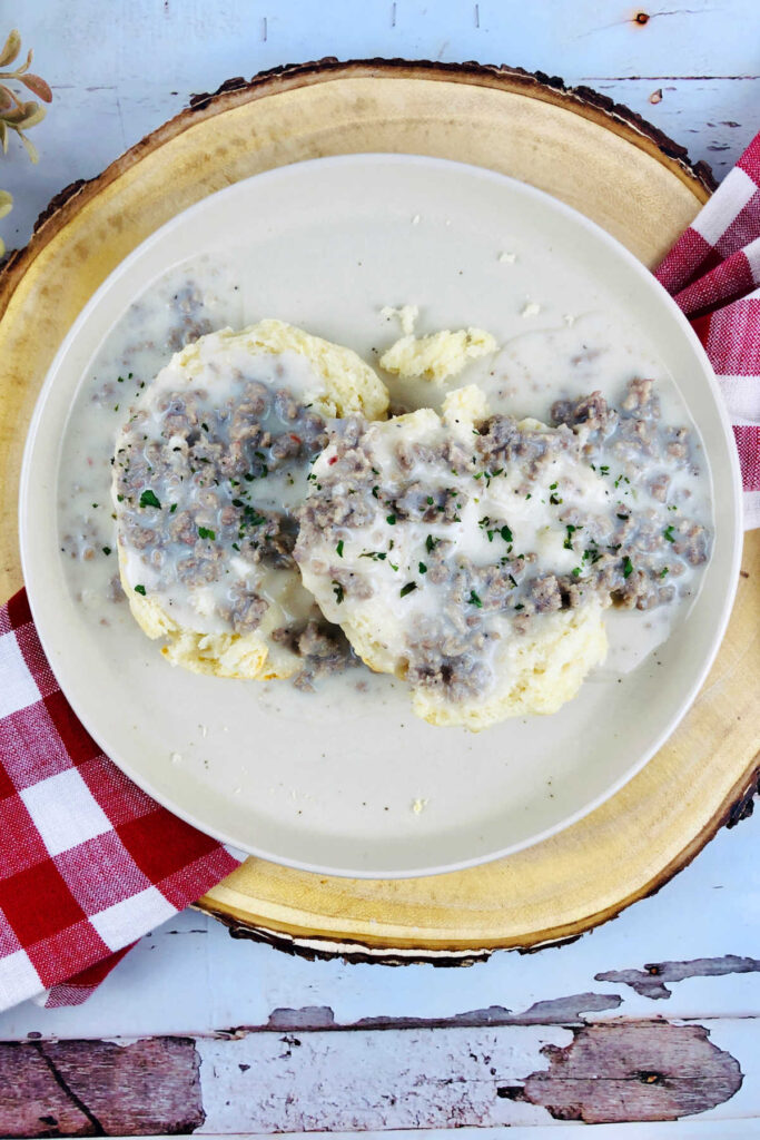 Plate of fluffy biscuits topped with gravy, ready to eat. 