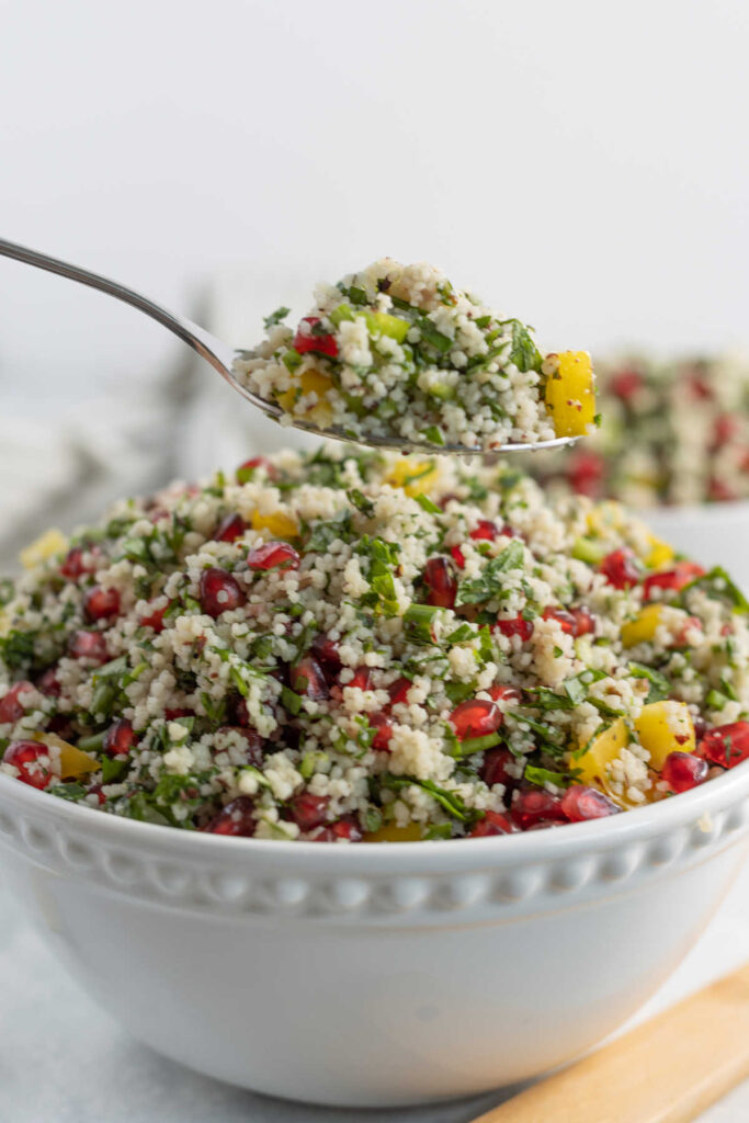Spoonful of pomegranate couscous salad, ready to be served on plate.
