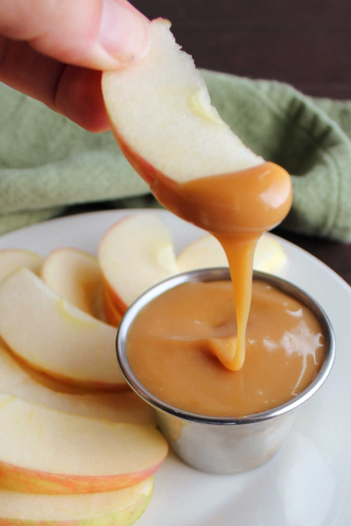 Apple slice with thick caramel dip dripping off it. 