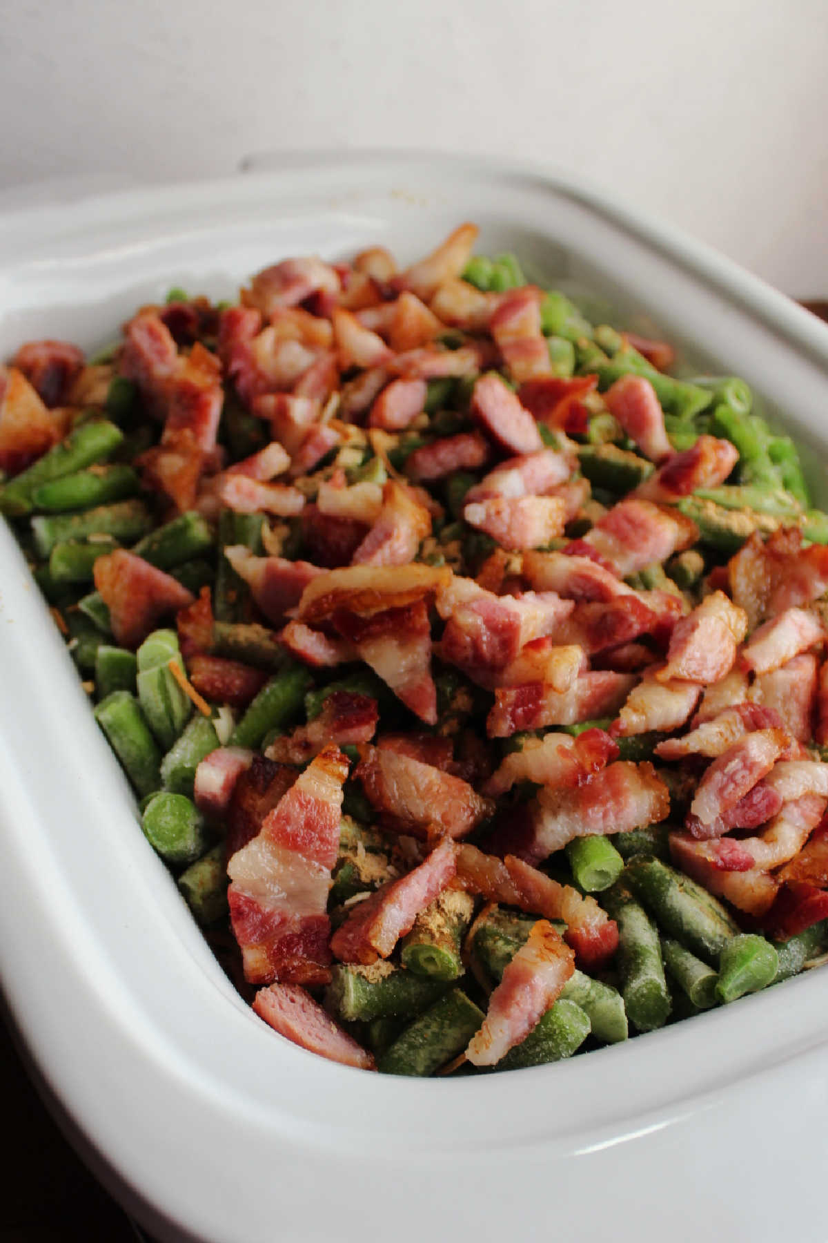 Lots of big bacon pieces over green beans in slow cooker.