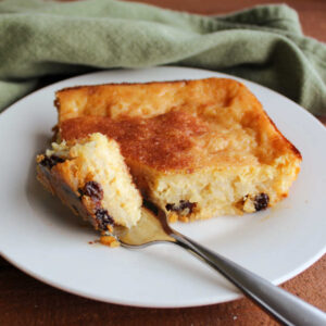 Bite of baked rice pudding with raisins on fork ready to eat.