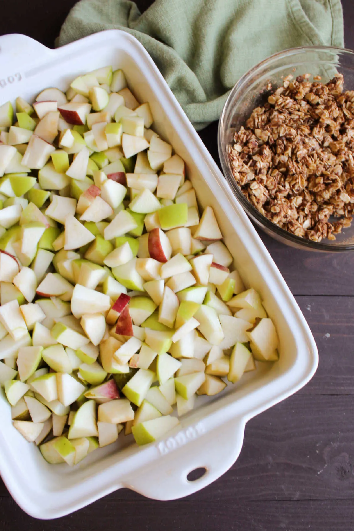 Pan of diced apples next to bowl of oat topping.