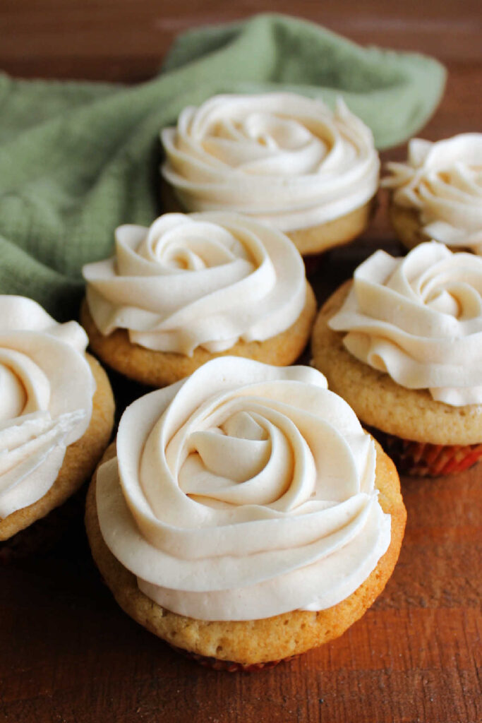 Rosettes of cinnamon buttercream piped on top of cupcakes. 