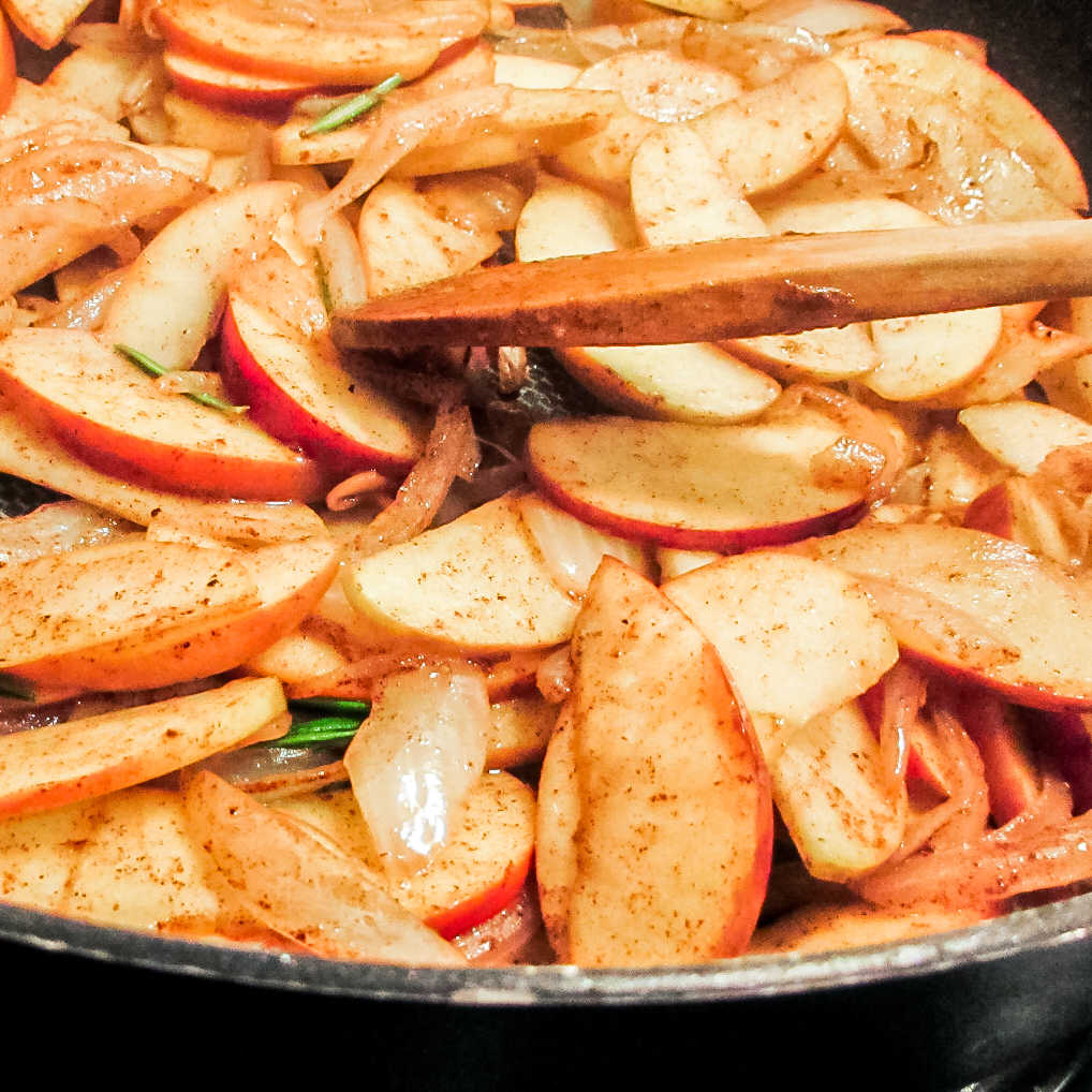Apples and onions cooking in skillet.