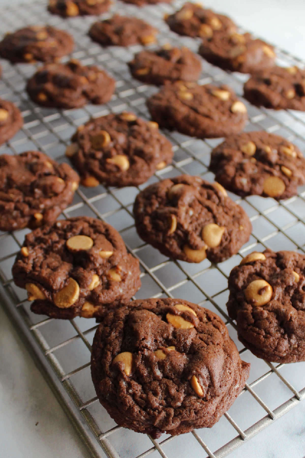 Freshly baked chocolate cake mix cookies with peanut butter chips on wire cooling rack.