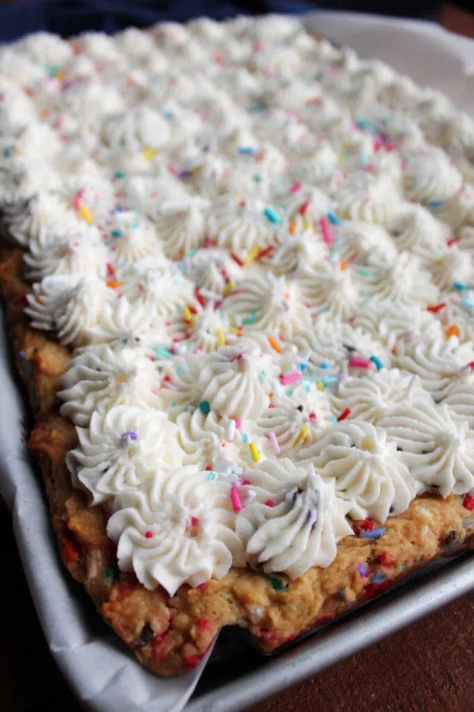 Cookie bars covered with stars of funfetti buttercream frosting and extra sprinkles.