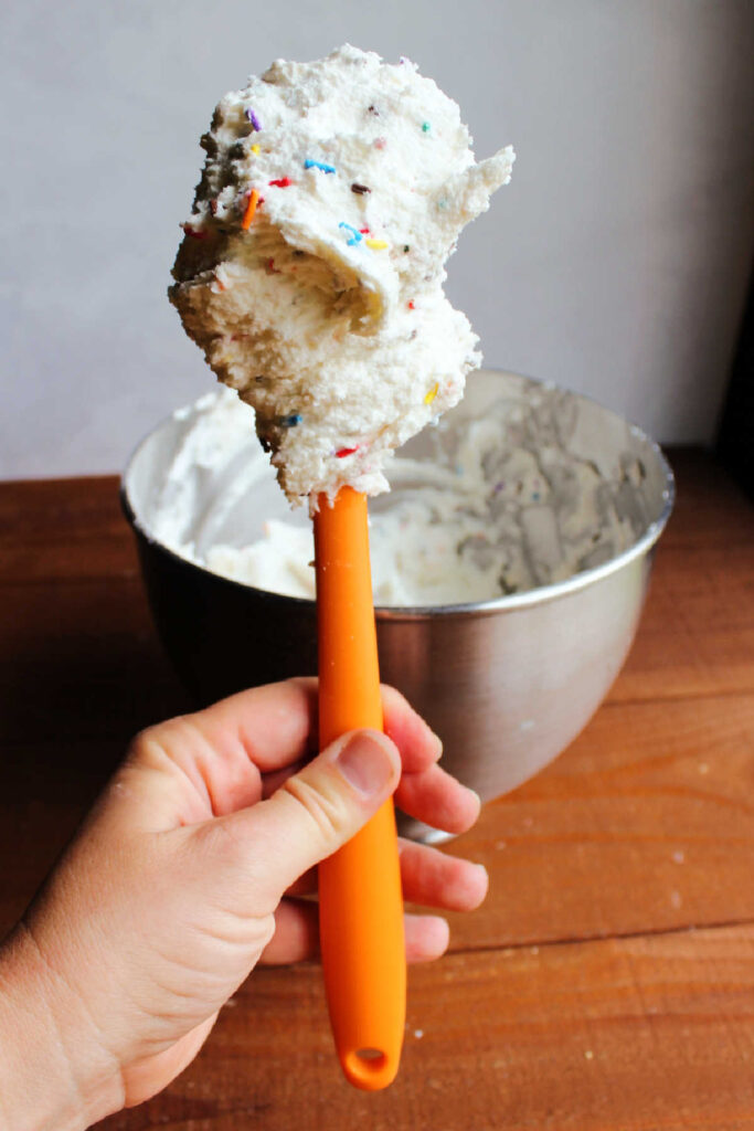 Spatula filled with colorful sprinkle funfetti frosting. 