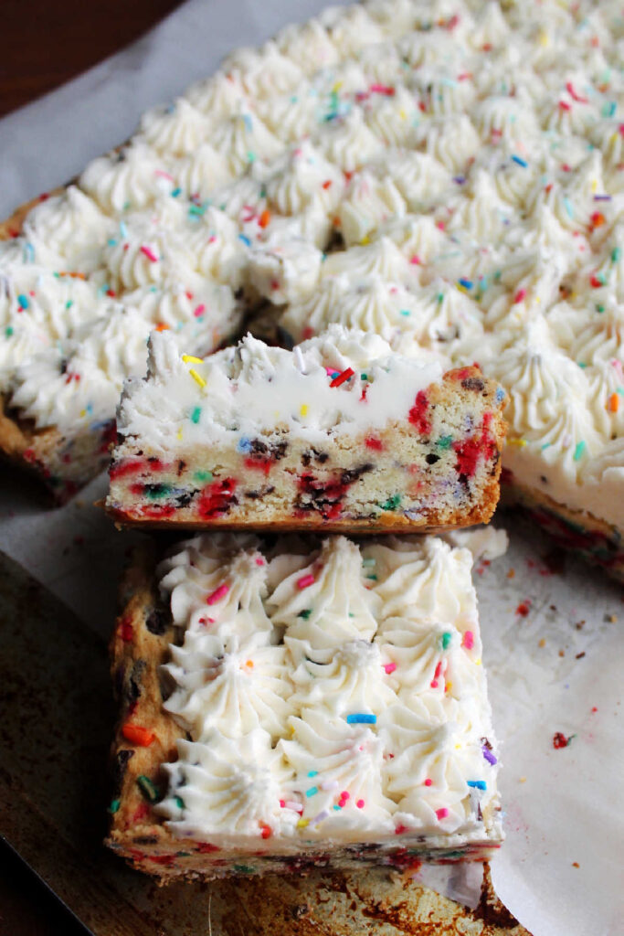 Side of sugar cookie bar with sprinkles baked inside and more sprinkles in frosting.