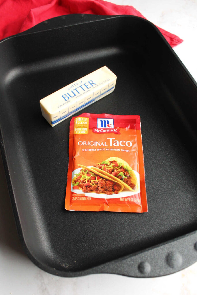 Packet of taco seasoning and stick of butter in roasting pan.