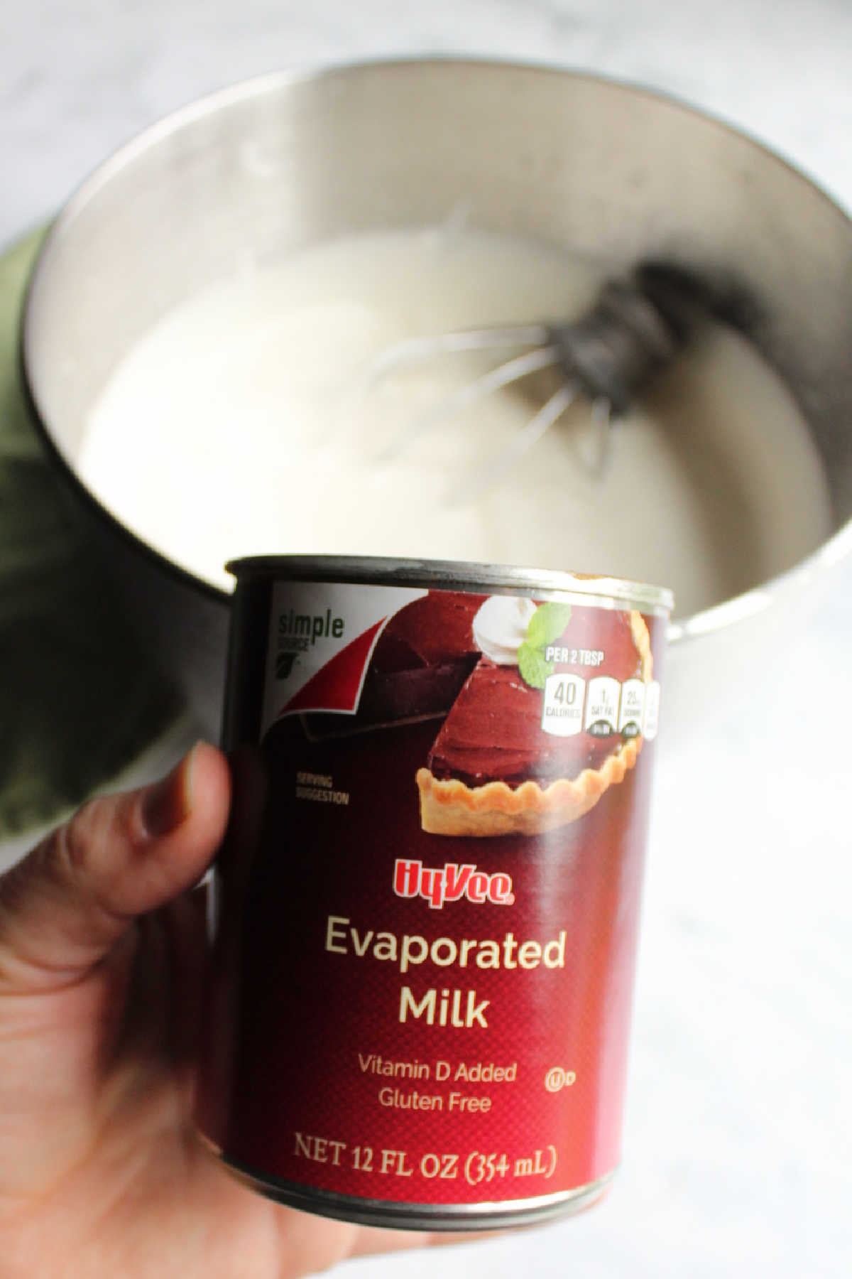 Can of evaporated milk in front of mixer bowl and beater.