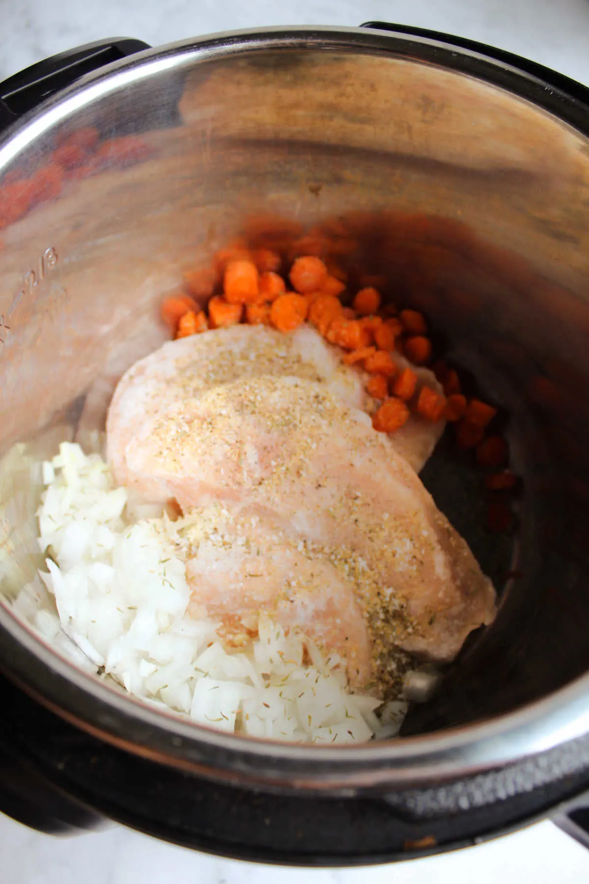 Frozen chicken with diced onion and carrots in instant pot.