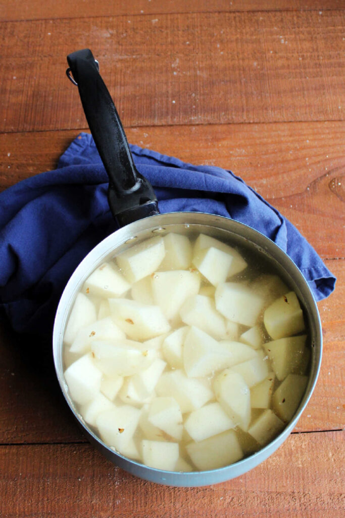 Pot filled with water and hunks of peeled potato ready to boil