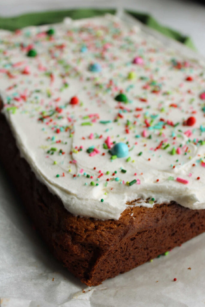 Corner whole gingerbread cookie bar with buttercream and sprinkles on top.